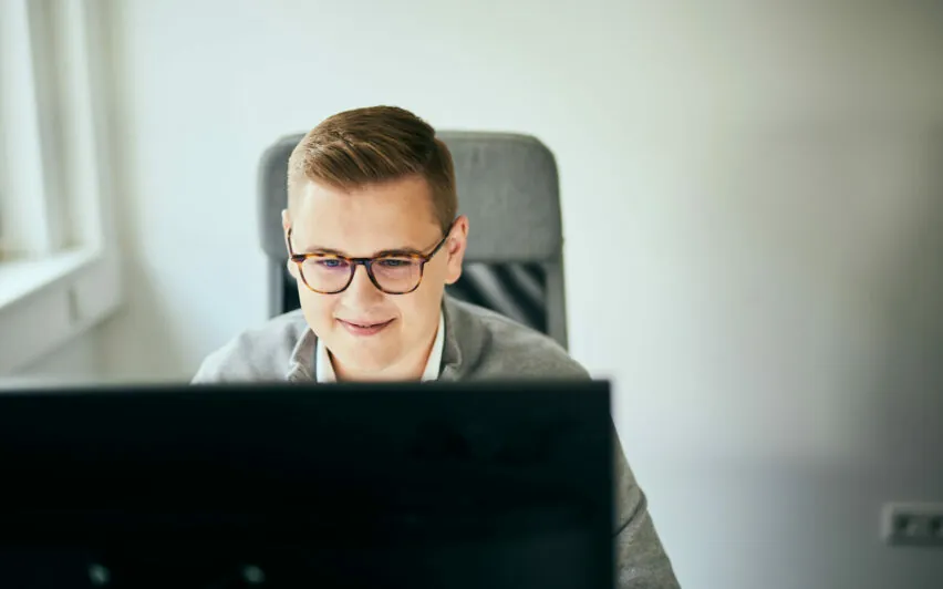 Foto von einem Mann mit Brille, der in einen Computerbildschirm schaut.