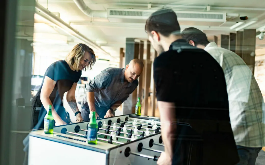 Vier Kollegen beim Tischfußball in der Pause.