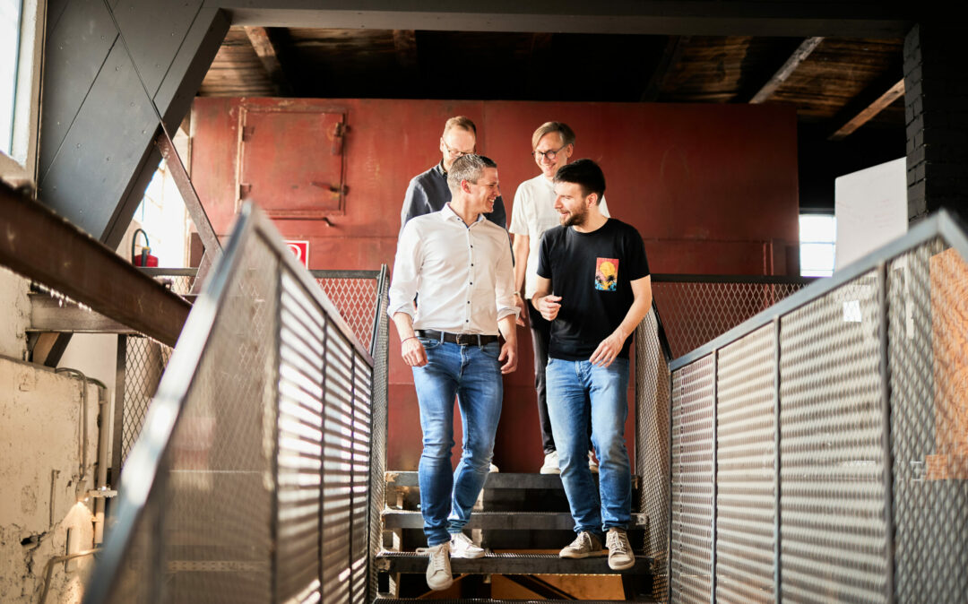 Vier Männer, die eine Treppe runter gehen und sich unterhalten.