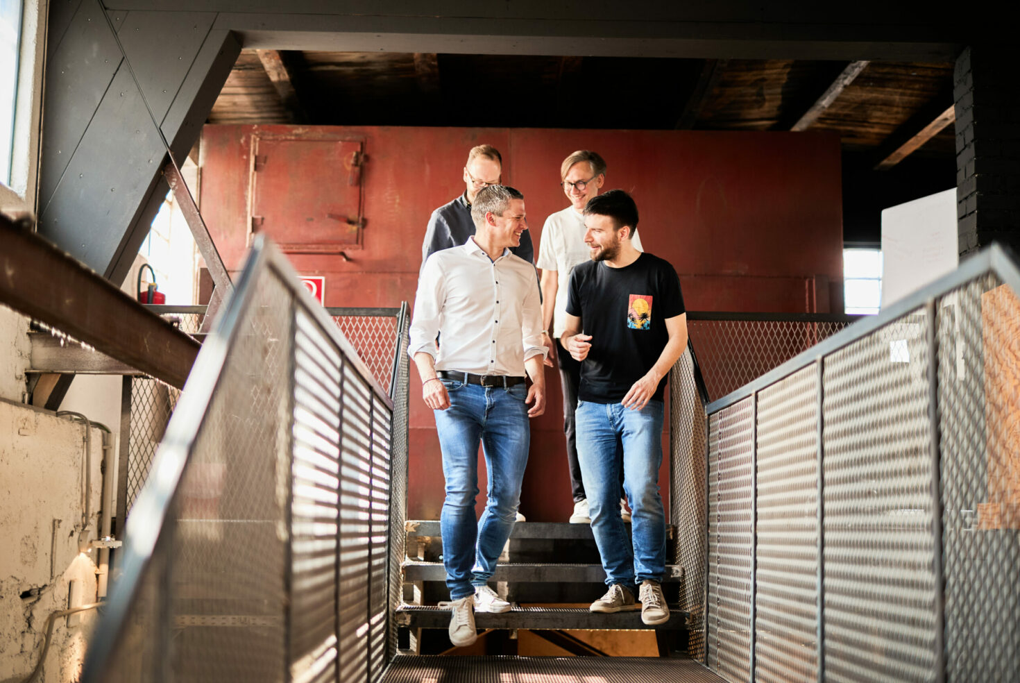 Four men walking down a flight of stairs and talking.