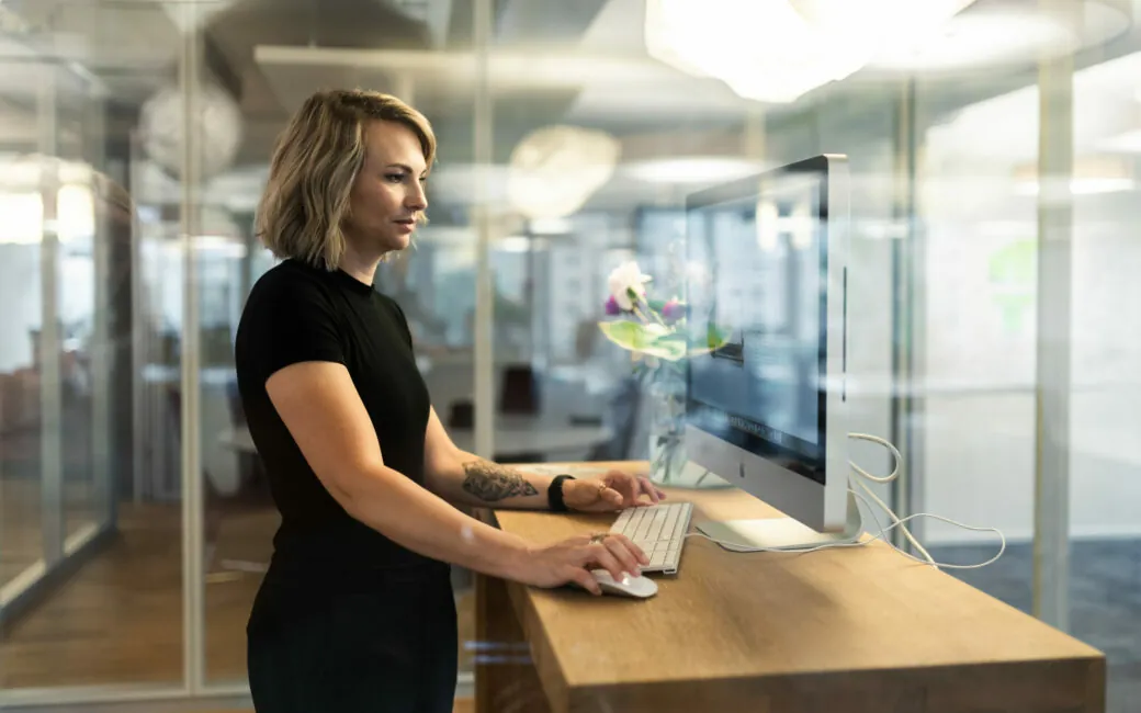 Foto von einer jungen Frau, die am Stehtisch arbeitet.
