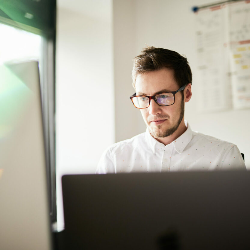 Man with glasses looking at a computer screen.