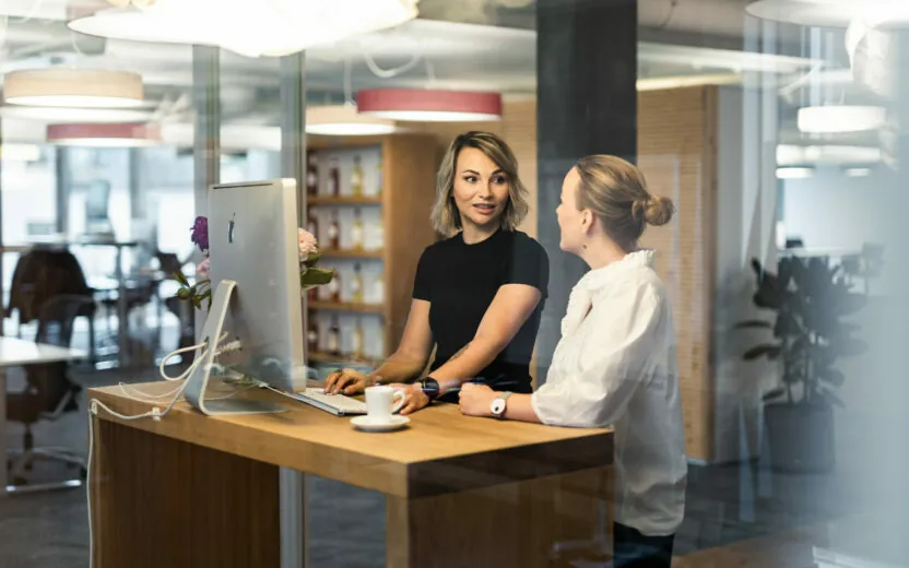 Two women talking to each other at a standing workstation