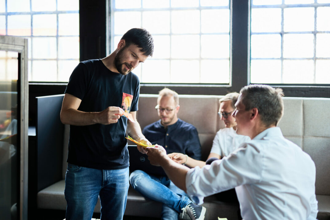 Photo of a young man handing out post-its to his colleagues.