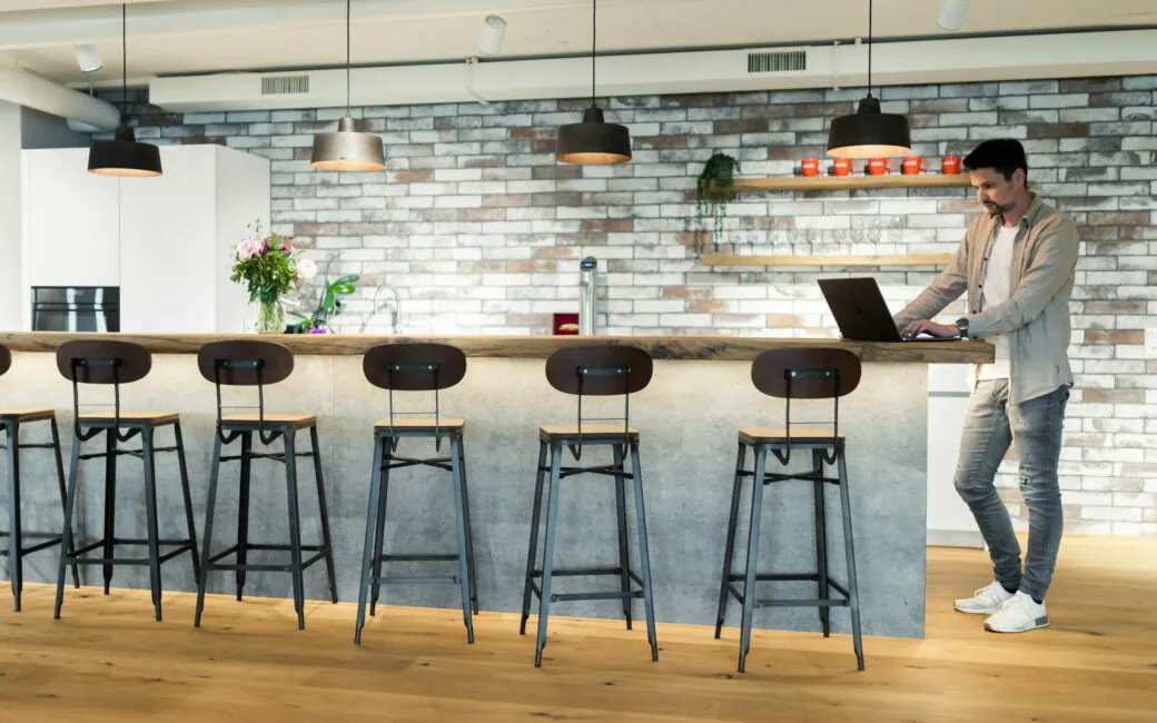 Junger Mann der mit seinem Laptop an einer Office-Bar arbeitet.