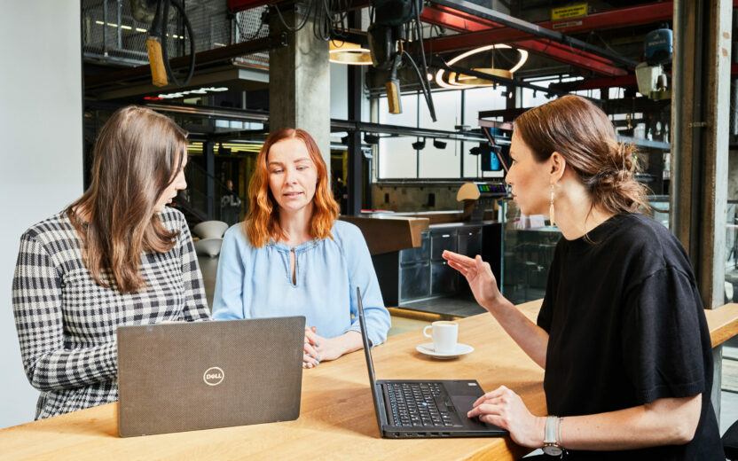 Photo of a young woman explaining a strategy to her two colleagues.
