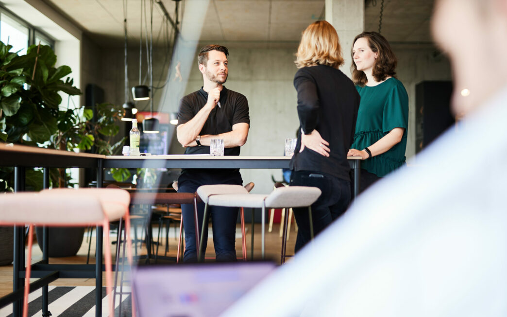 Photo of a man talking to two female colleagues about a project.