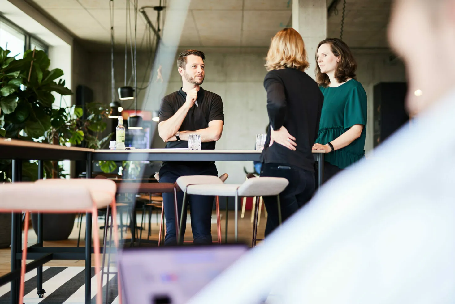 Photo of a man talking to two female colleagues about a project.