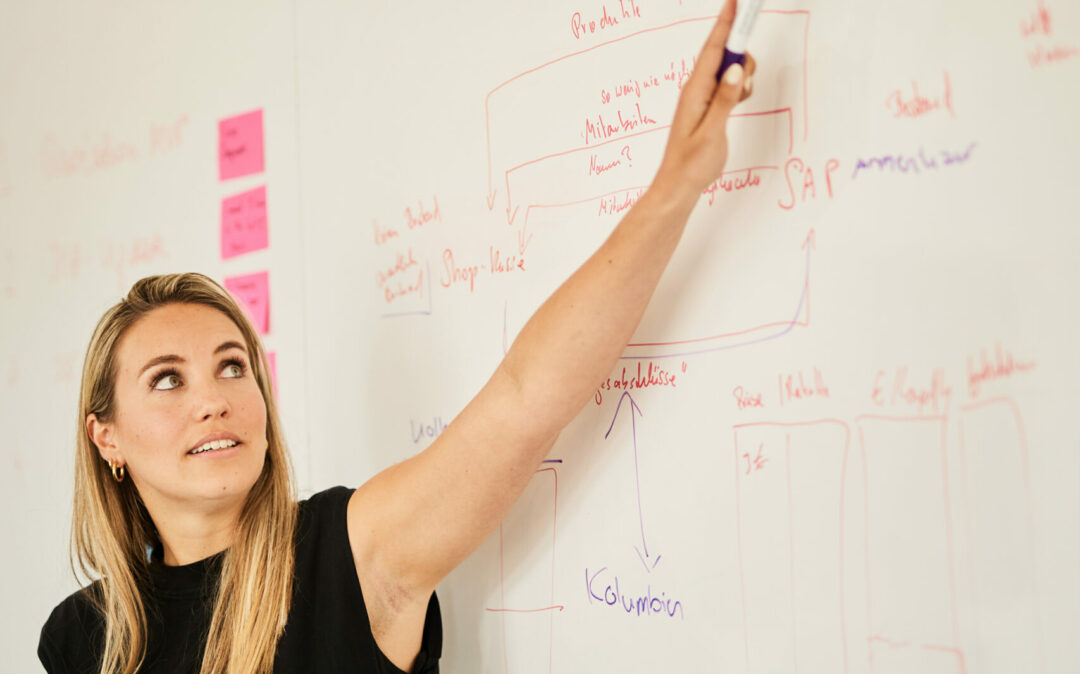 valantic Mitarbeiterin zeigt auf ein Whiteboard mit Schrift darauf