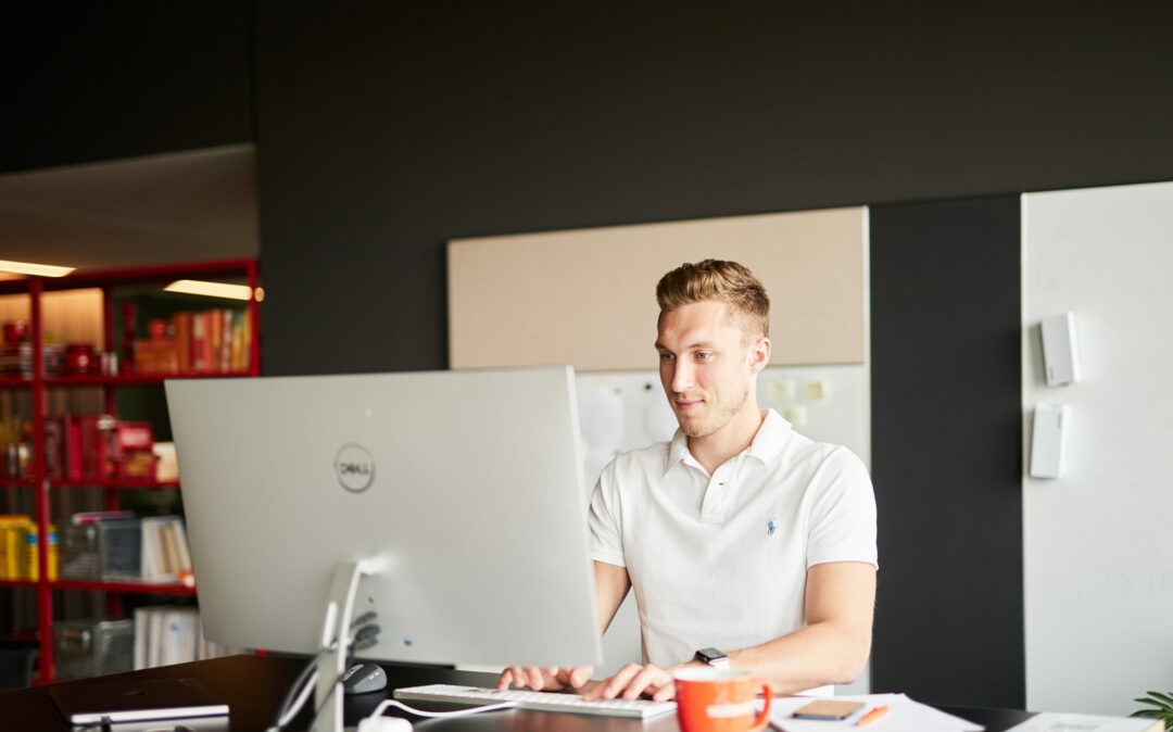 Photo of a young man working, looking at a comupter screen.