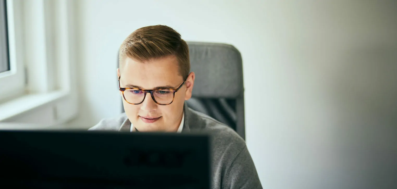 Photo of a man with glasses looking at a computer screen.