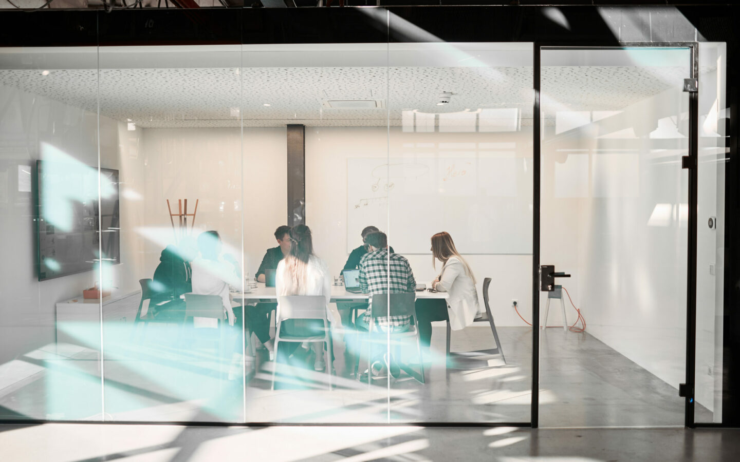 Photo of a group holding a meeting in a room with glass walls.