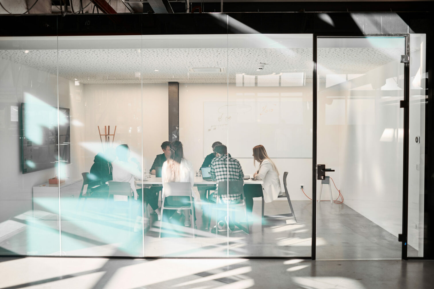 Photo of a group holding a meeting in a room with glass walls.