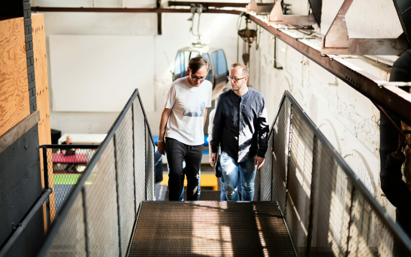 Photo of a smiling man with a glass of water standing at the office bar with his colleagues.
