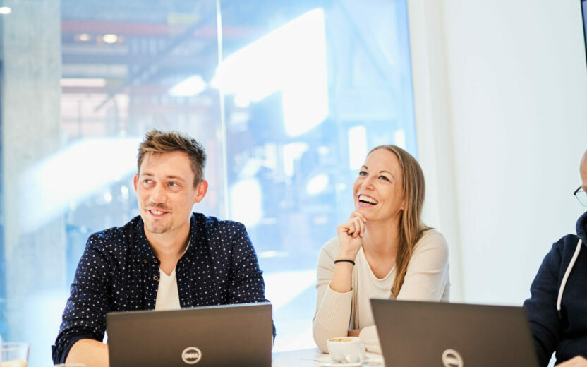 Picture of a laughing woman and a man sitting in a meeting.