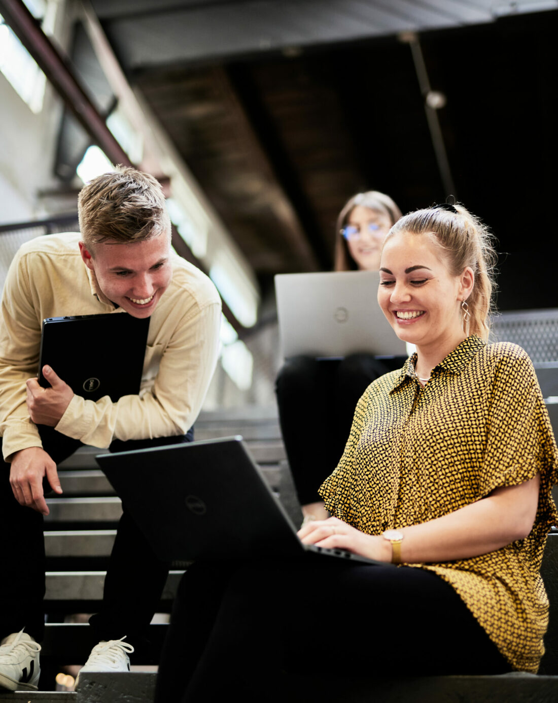 Photo of a young woman and a young man sitting on steps and working on a presentation on a laptop.