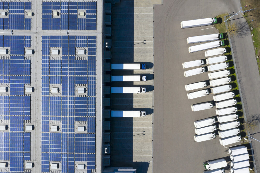 Aerial view of trucks being loaded with solar photovoltaic panels at logistics center, distribution warehouse