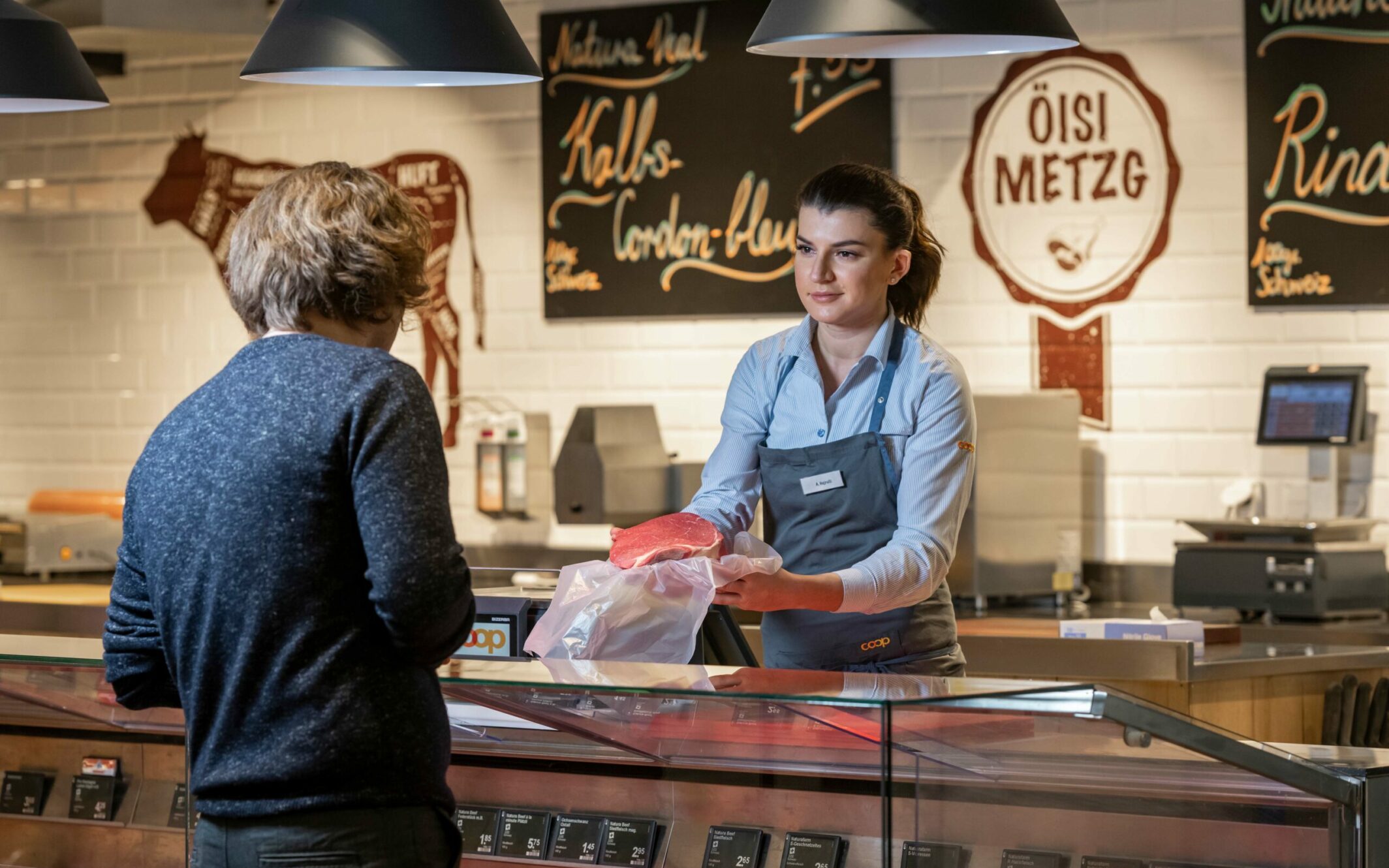Bild von einer Coop Mitarbeitenden an der Fleischtheke die einen Kunden bedient, Omnichannel Plattform