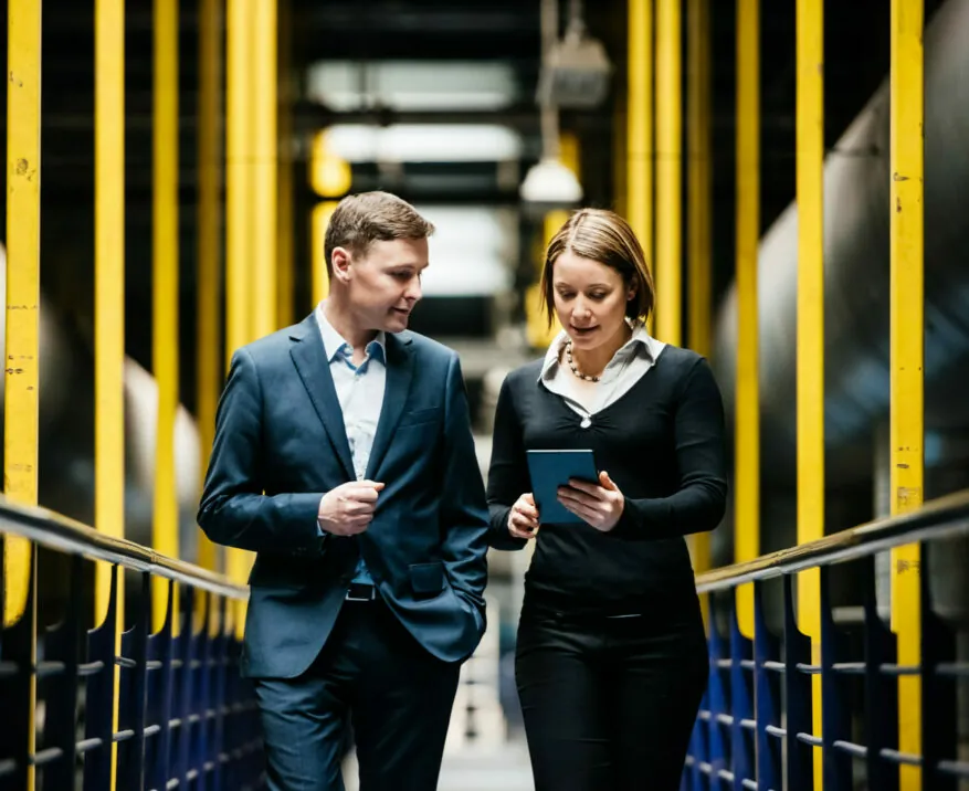 Zwei Geschäftsleute laufen durch Produktionshalle und reden über das valantic Vertragsmanagement bei BSH Haushaltsgeräte