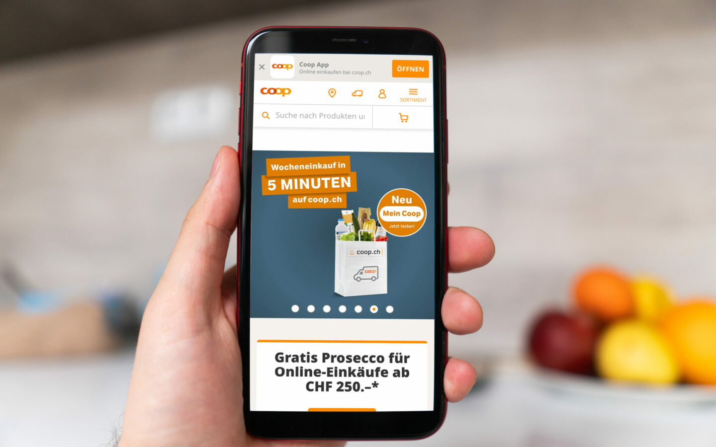 Bild von einem Smartphone im Vordergrund mit geöffneter coop.ch Startseite, SAP Commerce