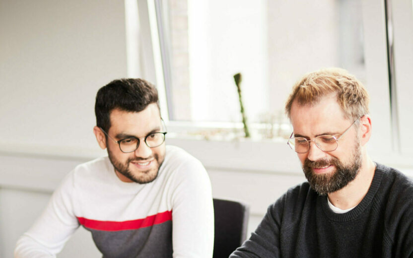 Foto von einem valantic-CX-Meeting, in dem ein Mann seinen Kolleg*innen etwas von einem Post-it vorliest.