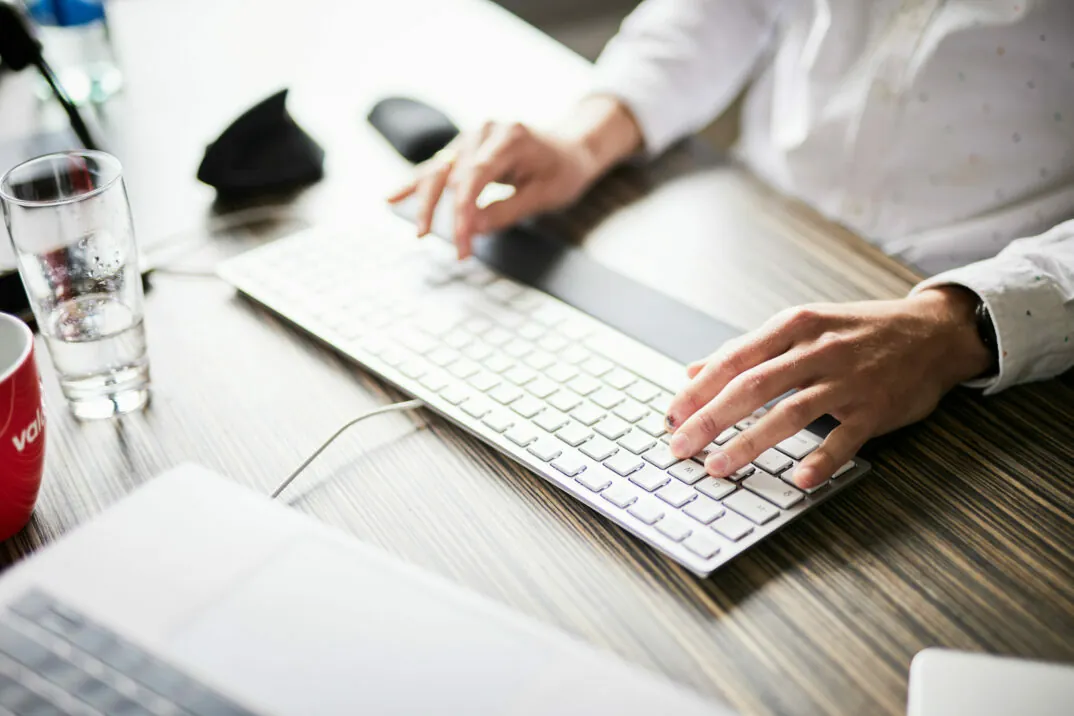 Close-Up von den Männerhänden eines Mannes, die auf einer Tastatur tippen.