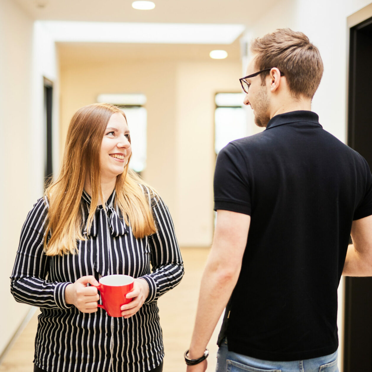 Photo of a woman and a man talking in the office hallway about the upcoming customer experience workshop.
