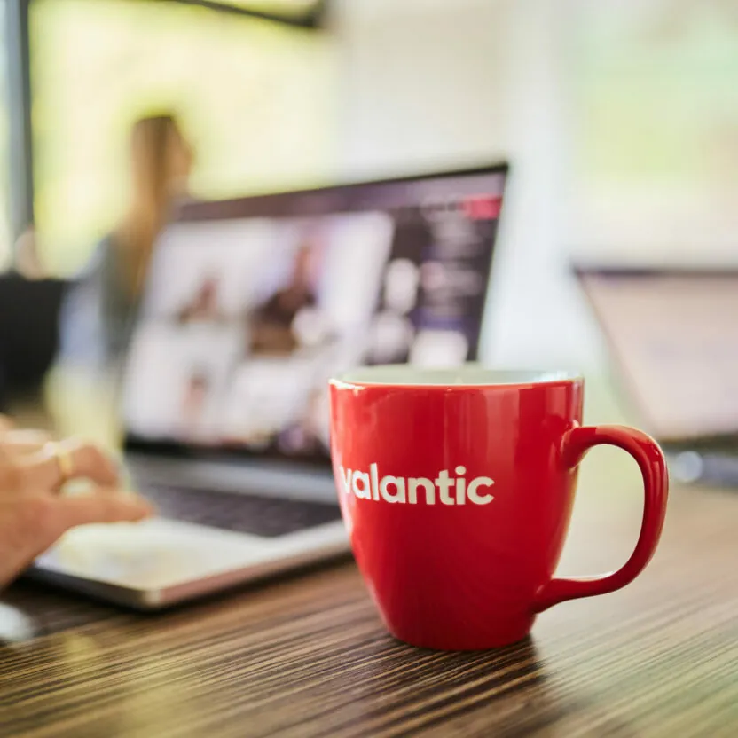 Close-up of a valantic cup standing in front of a laptop where someone is optimizing a customer journey.