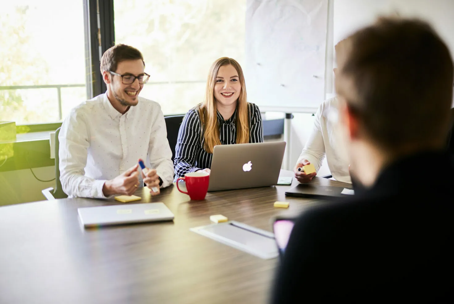 Photo of a smiling woman sitting next to her colleague in a customer experience meeting.