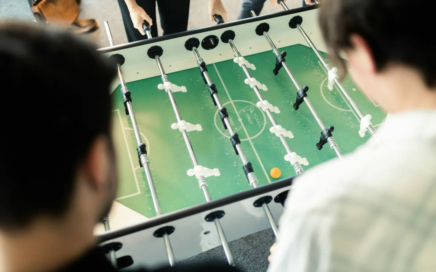 Foosball table, photographed from diagonally above, at which four valantic CX employees are playing.