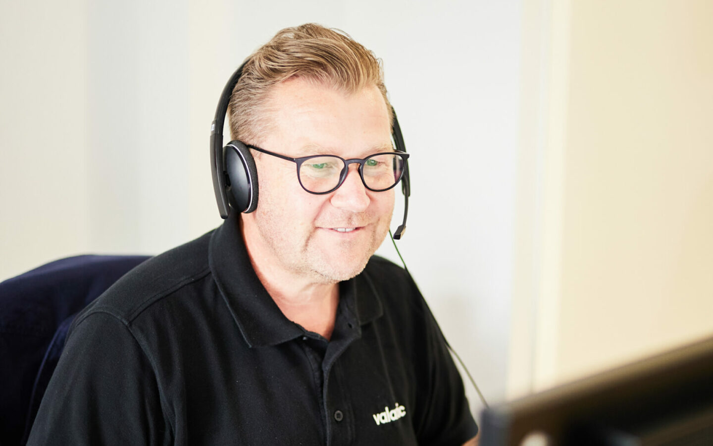 Middle-aged man sitting in front of a PC with headphones on.