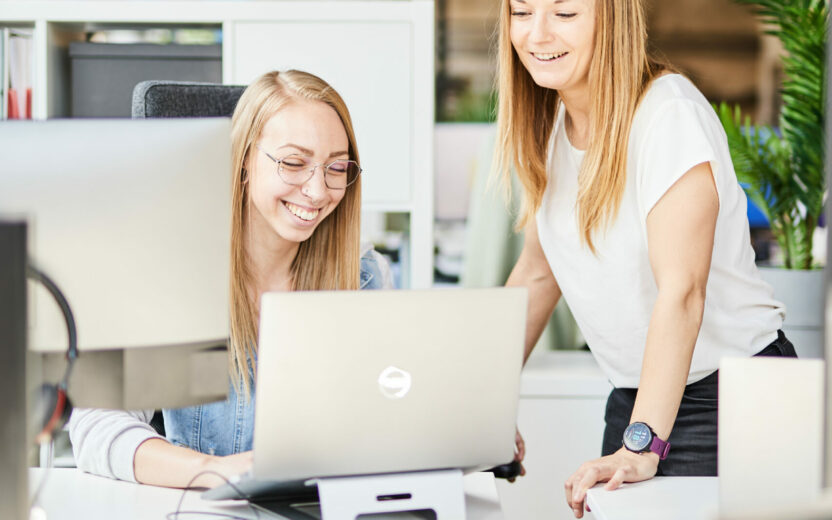 Shot of two valantic CX colleagues discussing something at their desks.