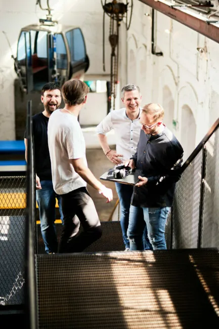 Foto von vier valantic-CX-Kollegen, die scherzend eine Treppe hinaufgehen.