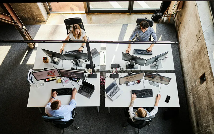 Aufnahme von einem valantic-CX-Arbeitsplatz mit vier Pimocore-Mitarbeiter*innen in Salzburg aus der Vogelperspektive.