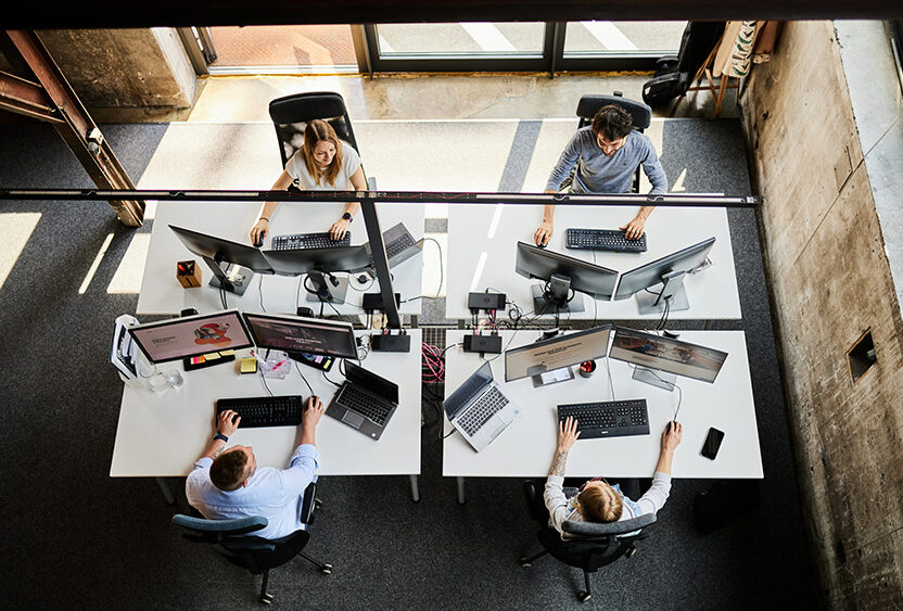 Bird's eye view of a valantic CX workstation with four Pimcore employees in Salzburg.