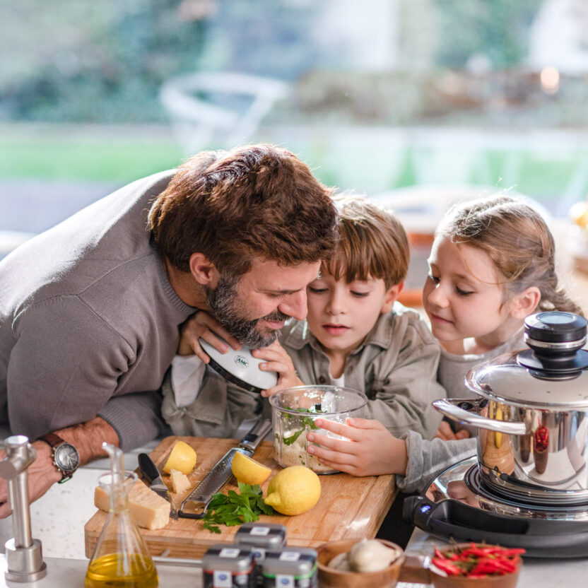 Foto von einem Mann mit seinen beiden Kindern beim Kochen in der Küche.