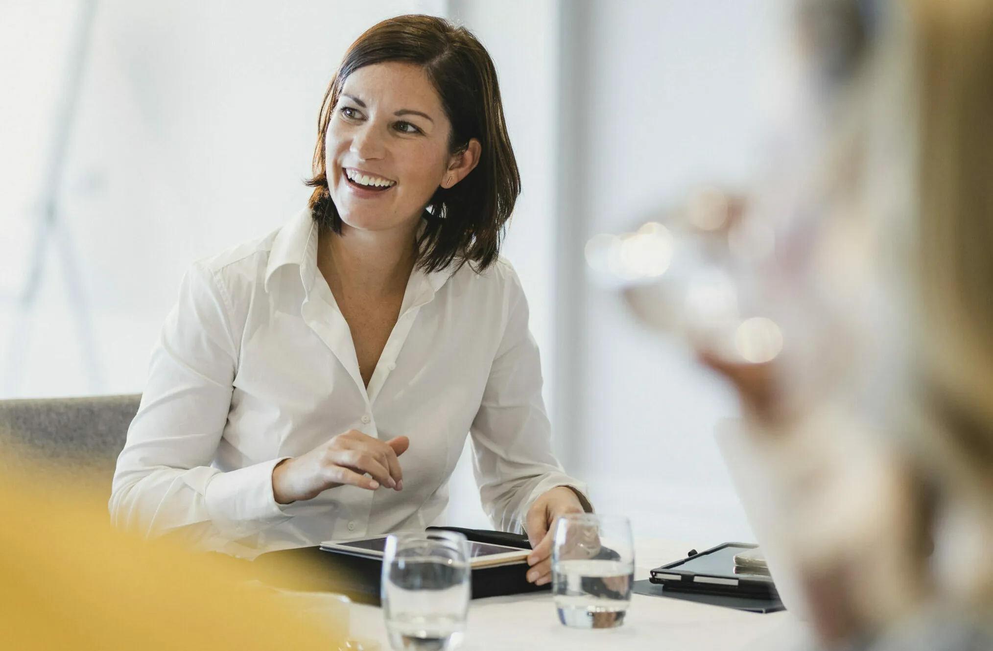 smiling businesswoman with tablet in meeting | valantic digital legal record in SAP