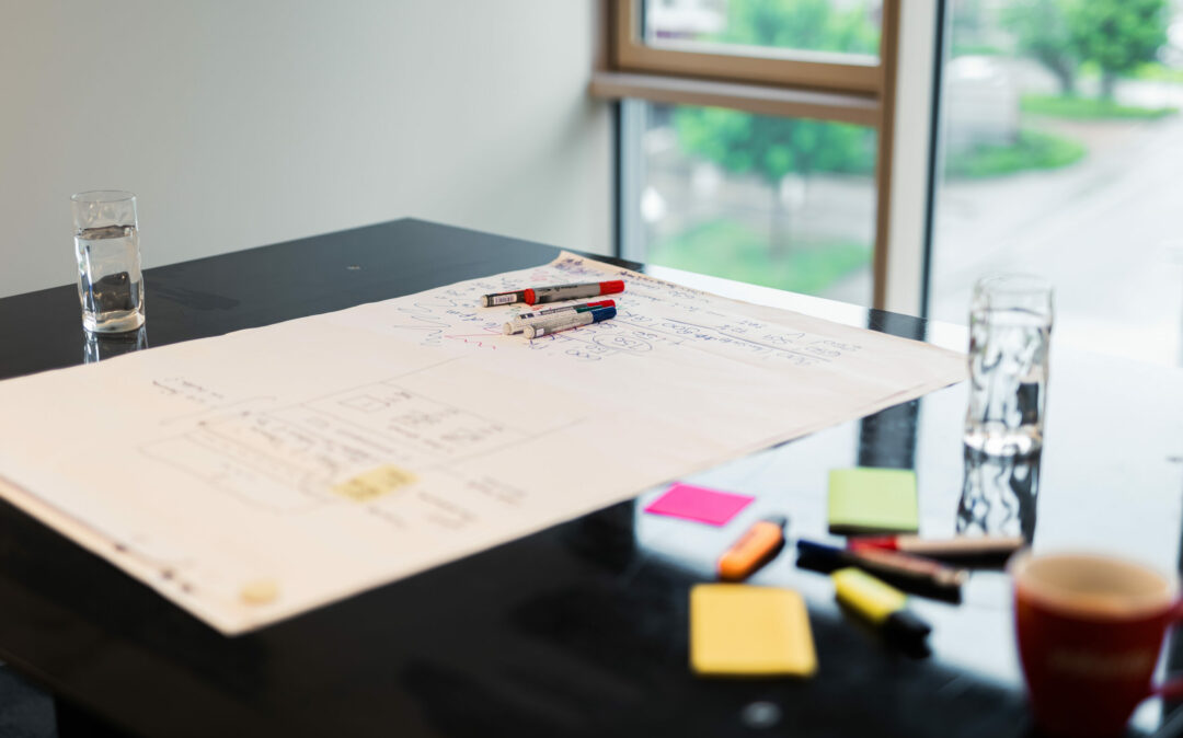Photo of three colleagues standing at a standing desk and working on a customer experience strategy.