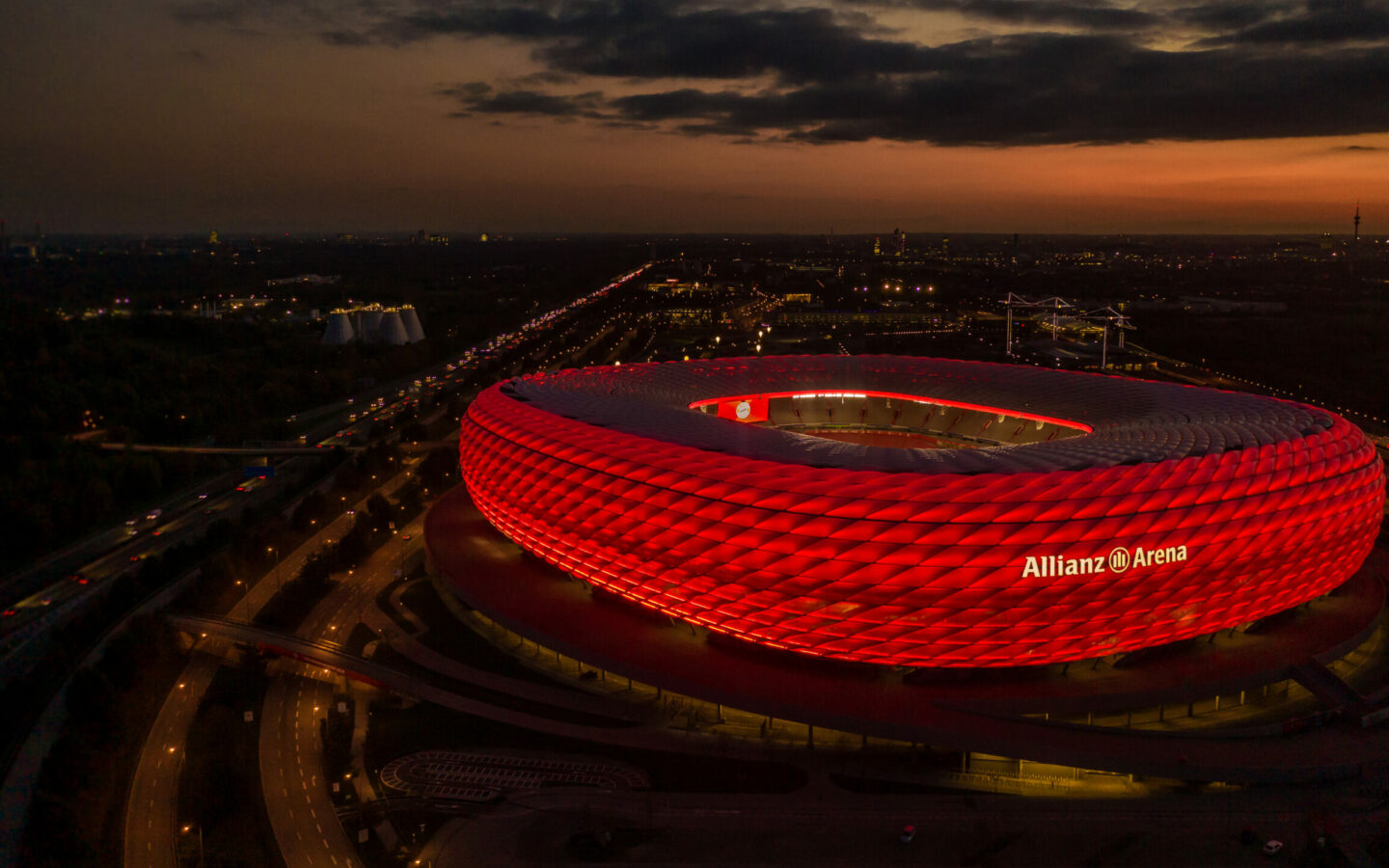Luftaufnahme der rot leuchtenden Allianz Arena bei Nacht