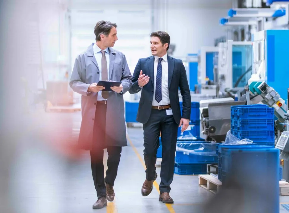 Two men are walking through a production hall and are talking