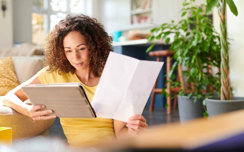 woman checking invoice with paper and tablet in her hands