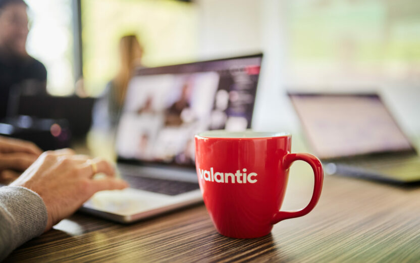 Close-up of a valantic cup standing in front of a laptop where someone is optimizing a customer journey.
