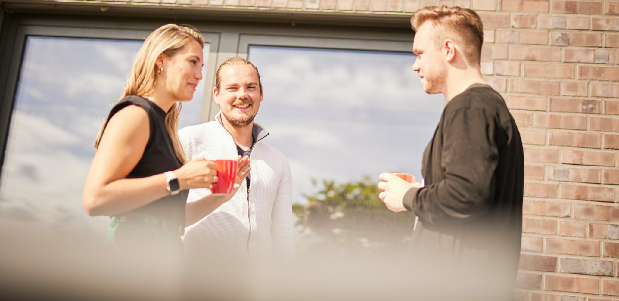 Drei Personen unterhalten sich auf der Terrasse das valantic CX-Büros in Langenfeld
