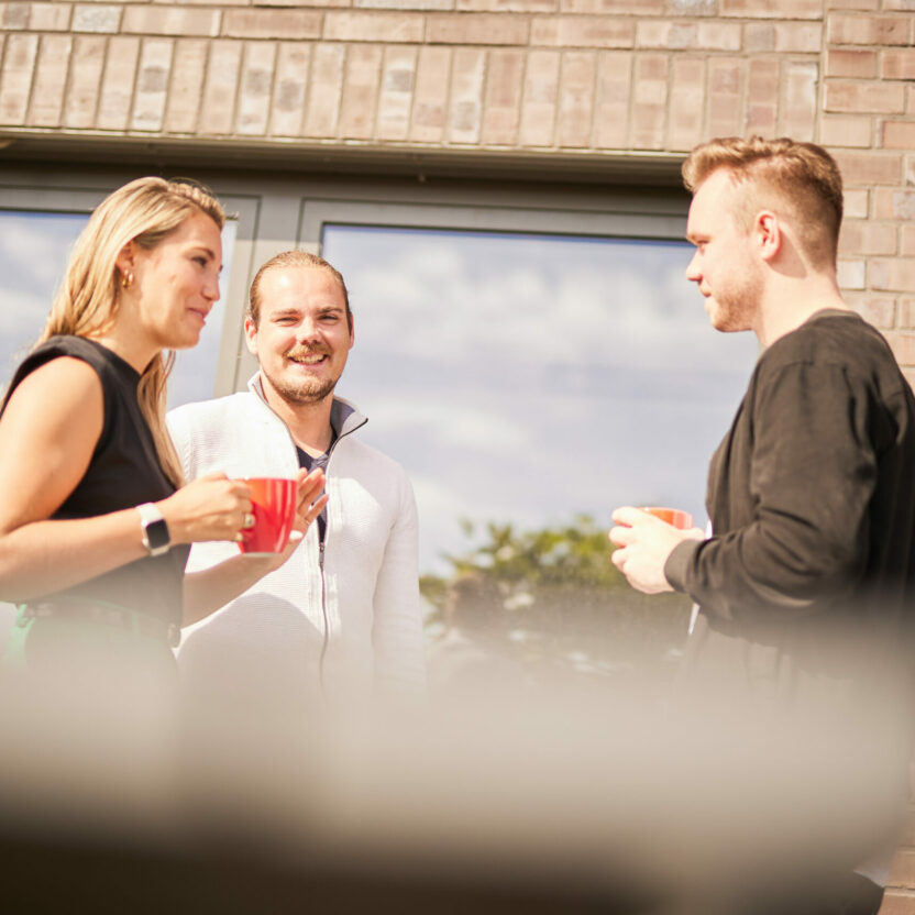 Drei Personen unterhalten sich auf der Terrasse das valantic CX-Büros in Langenfeld