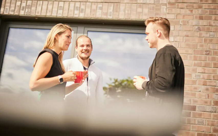 Drei Personen unterhalten sich auf der Terrasse das valantic CX-Büros in Langenfeld