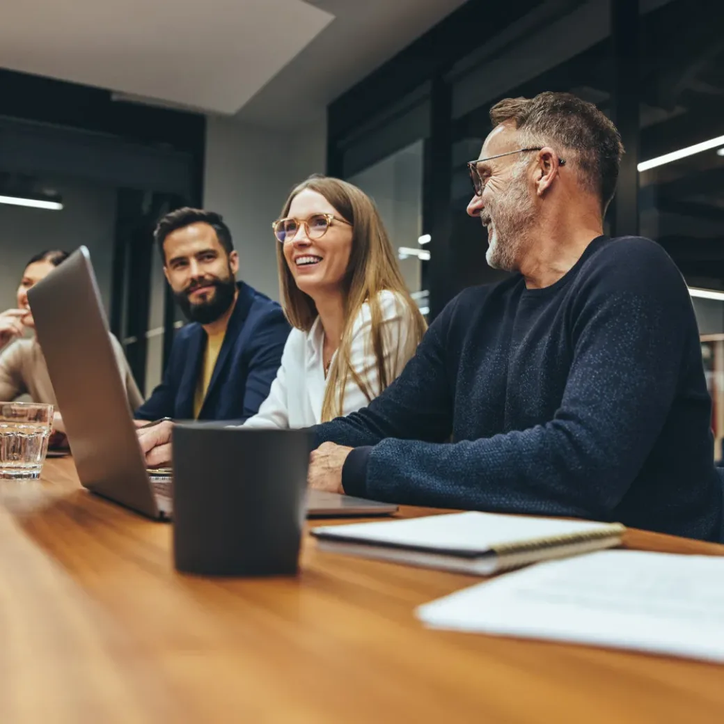 Successful group of businesspeople having a briefing in a boardroom. Happy businesspeople smiling while working together in a modern workplace. Diverse business colleagues collaborating on a project.