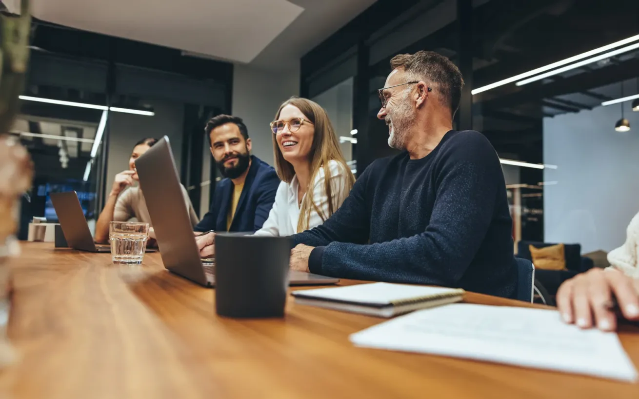 Successful group of businesspeople having a briefing in a boardroom. Happy businesspeople smiling while working together in a modern workplace. Diverse business colleagues collaborating on a project.