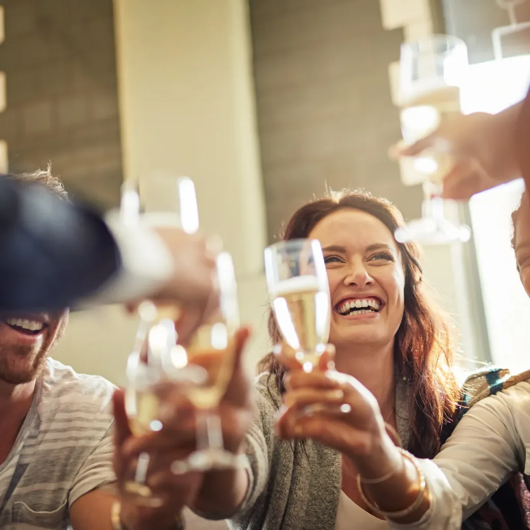 Eine Gruppe lächelnder Menschen, die in einem hellen Raum mit einem Glas Sekt auf eine erfolgreiche S&OP-Sitzung anstoßen.