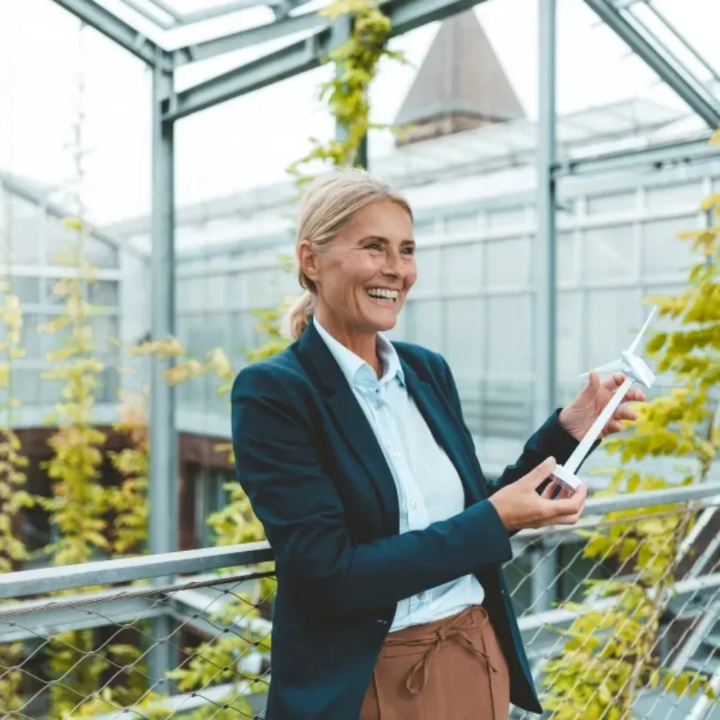 Happy agronomist with wind turbine model in garden center