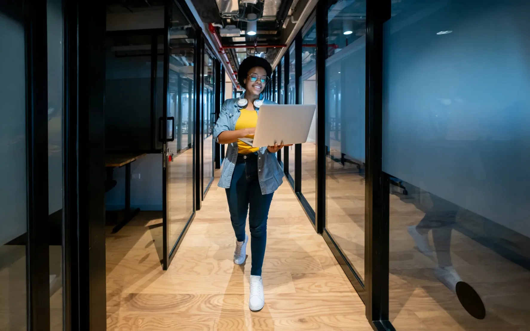 IT-Technikerin, die spät im Büro arbeitet, ihren Laptop benutzt und lächelt